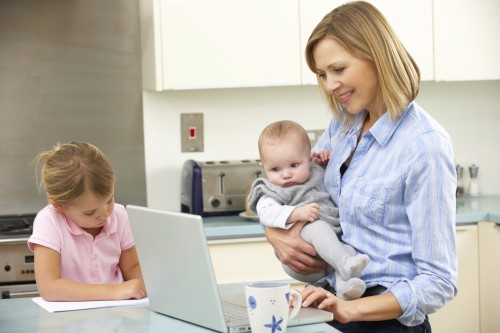 Мама з малюком на руках працює за ноутбуком