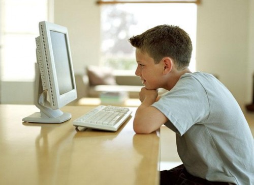 Підліток дивиться в монітор комп'ютера