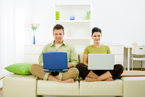 Чоловік і дружина сидять на дивані з ноутбуками в руках
