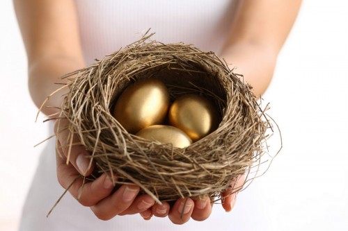 Дівчина тримає в руці пташине гніздо з золотими яйцями